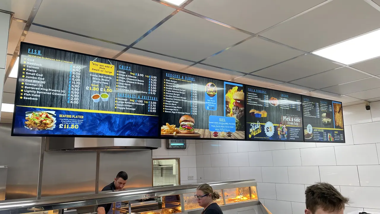 Digital menu screens above a busy food counter