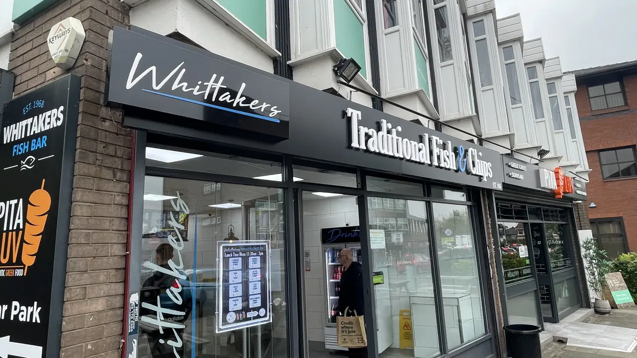 Black fascia sign with illuminated lettering above a fish and chip shop